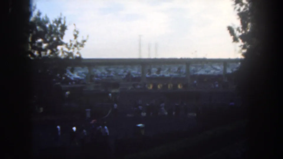 Disneyland, California, 1962, viewed from a shaded opening as guests walk below an elevated track or walkway.