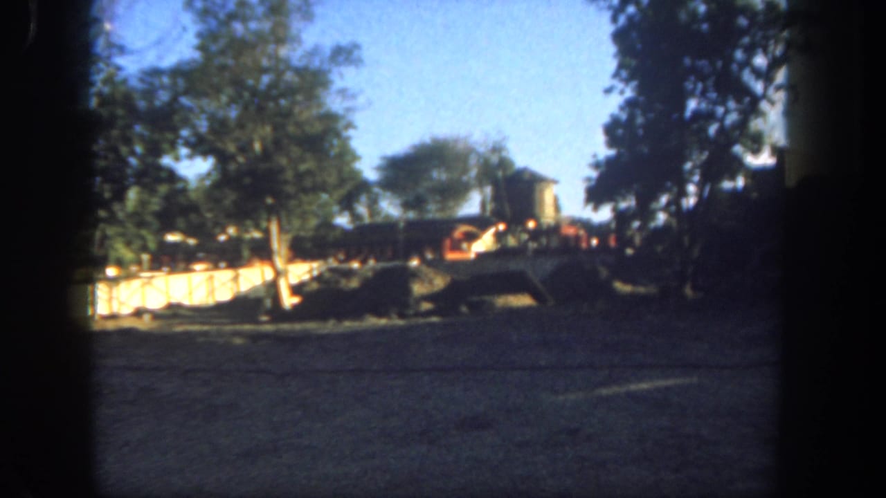 Construction area with trees, barriers, and a partially visible columned building at the right edge.