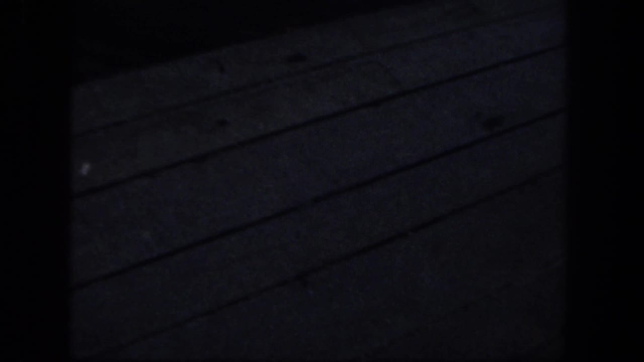 Mostly dark frame with faint diagonal lines from a wooden surface or dock.