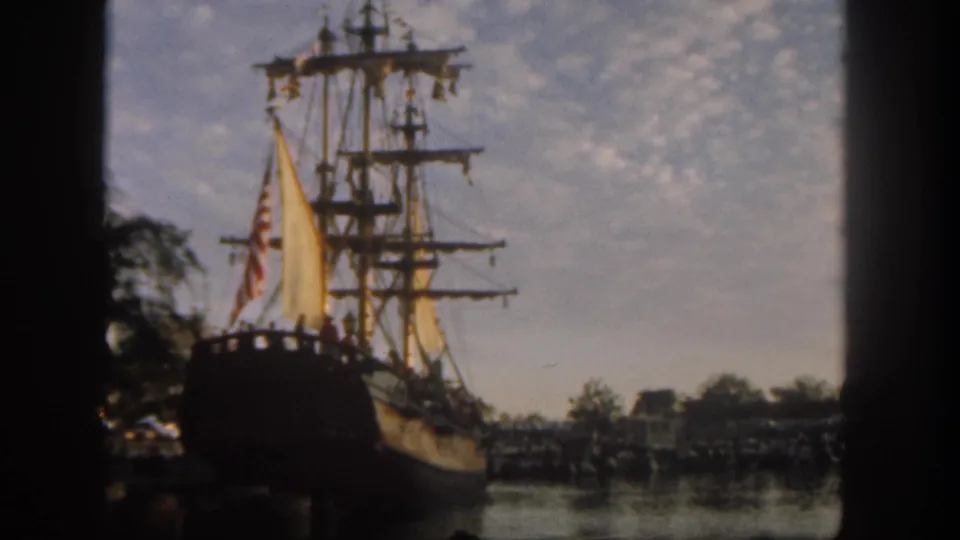 Soft 8mm frame from Disneyland in 1962 showing the docked sailing ship through a dark vertical foreground edge.
