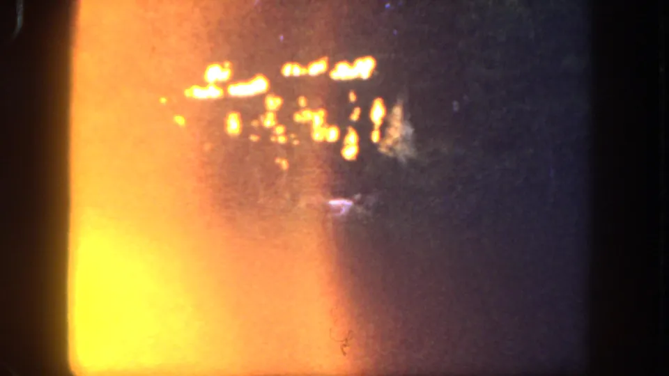 1962 Disneyland 8mm frame with flames in a dark wooded area and a strong orange light leak along the left side.