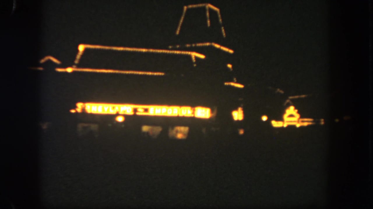 Dark nighttime view of an illuminated storefront facade and glowing sign.