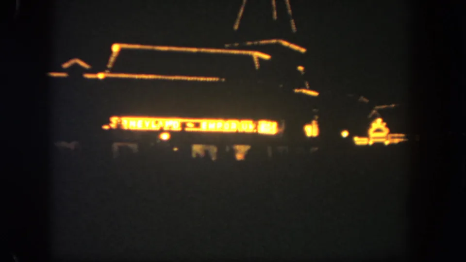 Final frame of the Disneyland Emporium at night, with the building roofline and sign glowing through grain and soft focus.