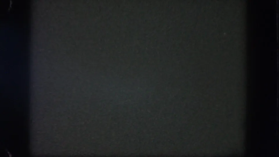 Dark 1962 8mm home-movie frame from Disneyland with faint grain, gate edges, and no identifiable people or landmarks.