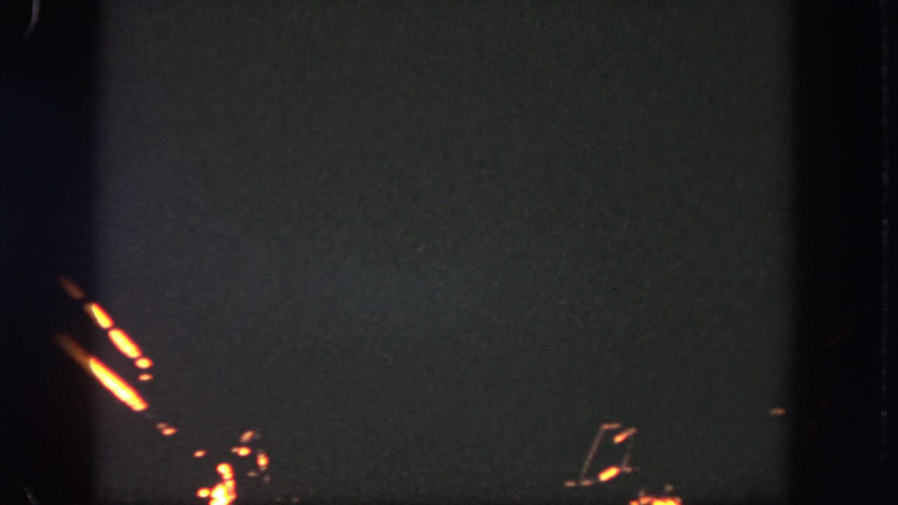 1962 Disneyland 8mm frame with clustered orange firework trails visible against a dark, grainy sky.