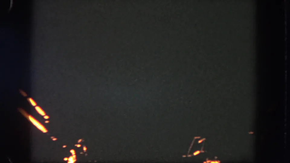 1962 Disneyland 8mm frame with clustered orange firework trails visible against a dark, grainy sky.