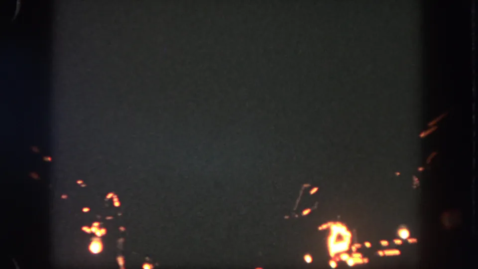 1962 Disneyland nighttime frame showing scattered orange sparks and a brighter glow near the lower right edge.