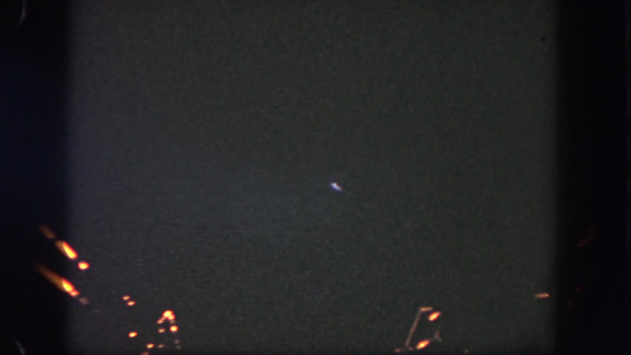 Dark sky with small orange firework streaks and scattered sparks near the lower frame.