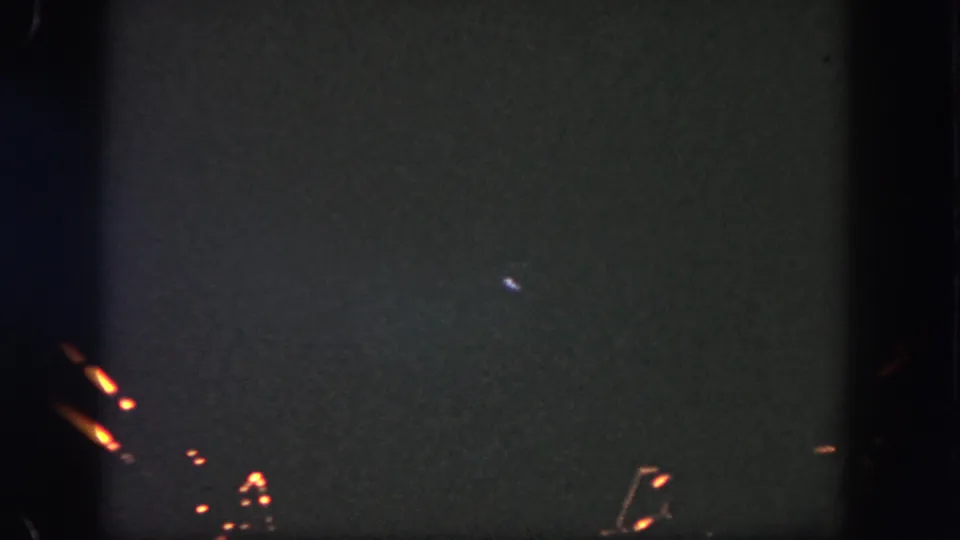 1962 Disneyland fireworks footage shows a dark night sky with orange pyrotechnic streaks and faint spark clusters on 8mm film.