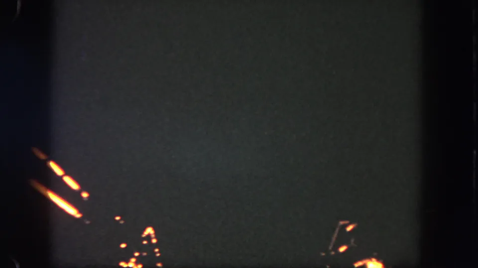A visitor-shot 8mm frame from Disneyland shows orange firework trails and scattered sparks against a dark night sky.