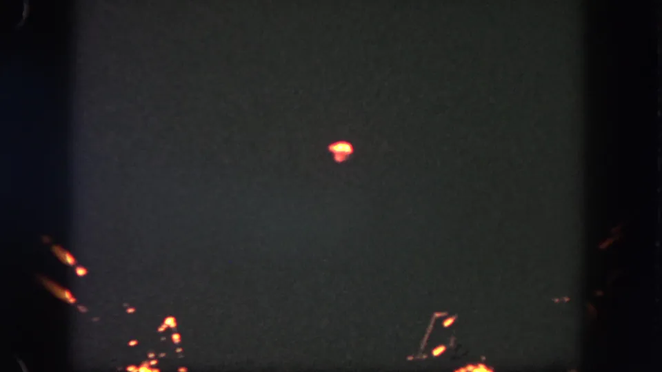 Final frame of the 1962 Disneyland fireworks clip shows small orange sparks and a glowing burst over a dark, grainy sky.