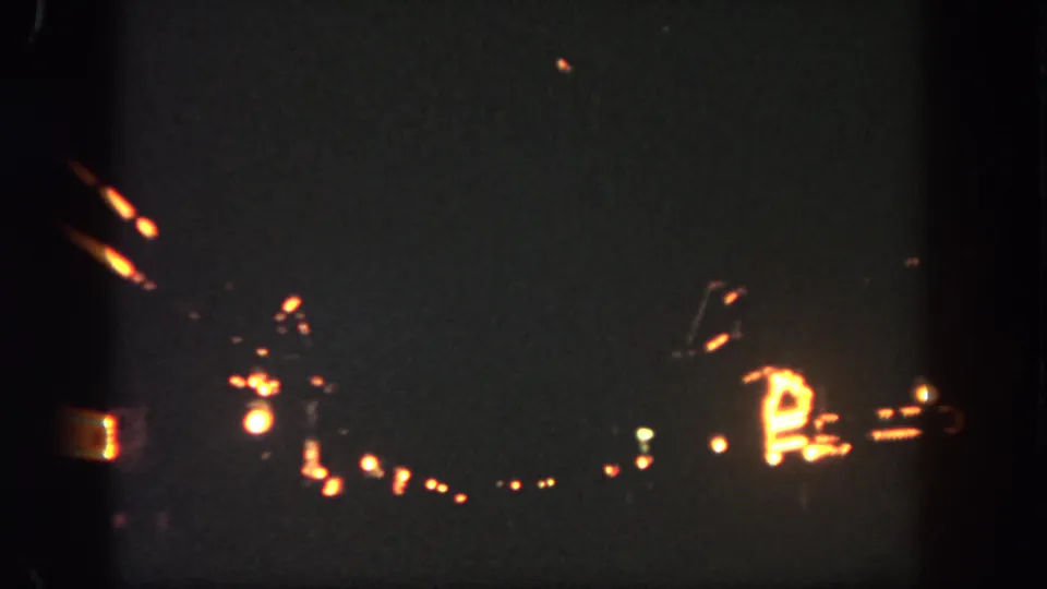 Low-light 1962 Disneyland home-movie frame with bright orange sparks, a curved fireworks trail, and visible frame-edge shadows.