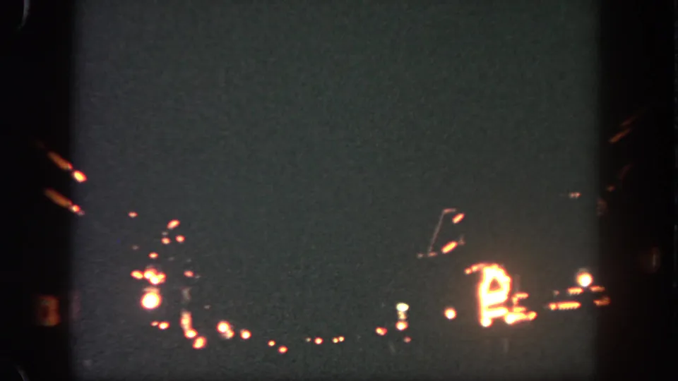 1962 Disneyland home-movie frame with dim Main Street-area lights, soft trails, and heavy low-light grain.