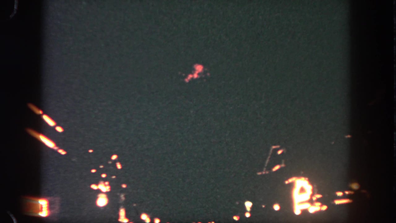 Red and white firework sparks against a dark sky with visible film frame edges.