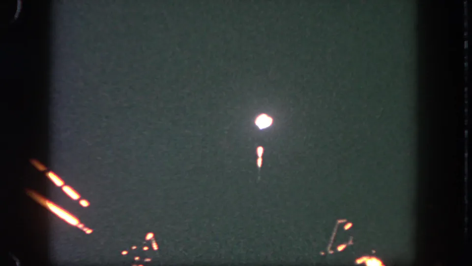 Final 8mm frame shows a bright white firework point and short glowing trail over a dark Disneyland night sky.