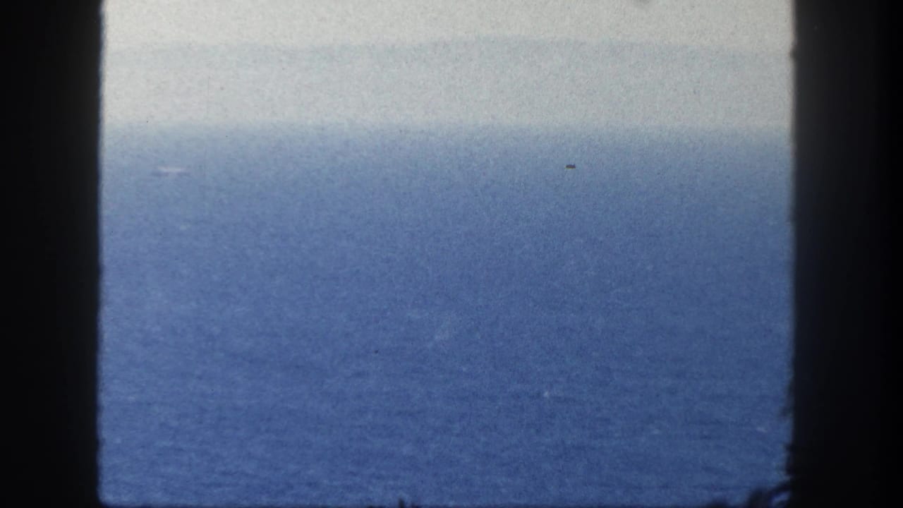 Open blue ocean and hazy sky divided by dark vertical frame edges.