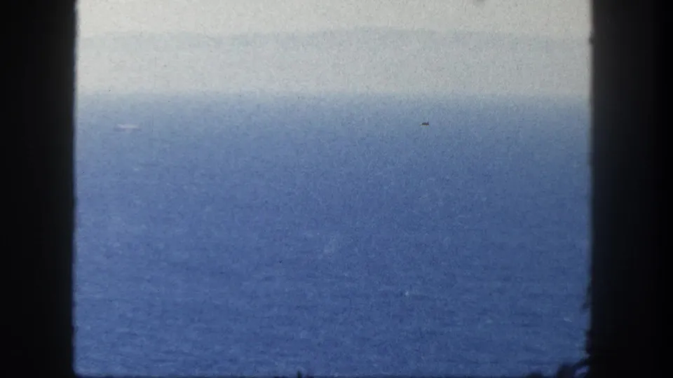 1962 San Diego coastal view with a hazy ocean horizon and dark vertical window or railing edges crossing the frame.
