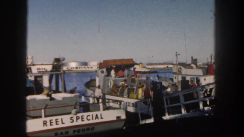 1962 San Diego harbor view of the San Pedro Special at a dock, with adults gathered near the boat and Mobil Oil tanks in the background.