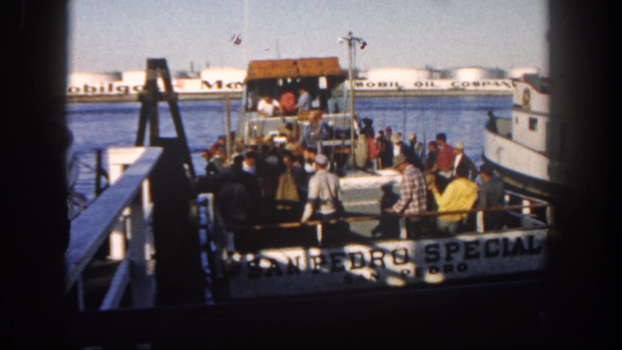 Crowd of adults on and beside the San Pedro Special with Mobil Oil tanks behind them.