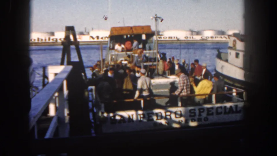 Adults board or stand near the San Pedro Special in 1962 San Diego, with dock structures, water, and Mobil Oil tanks visible behind the boat.