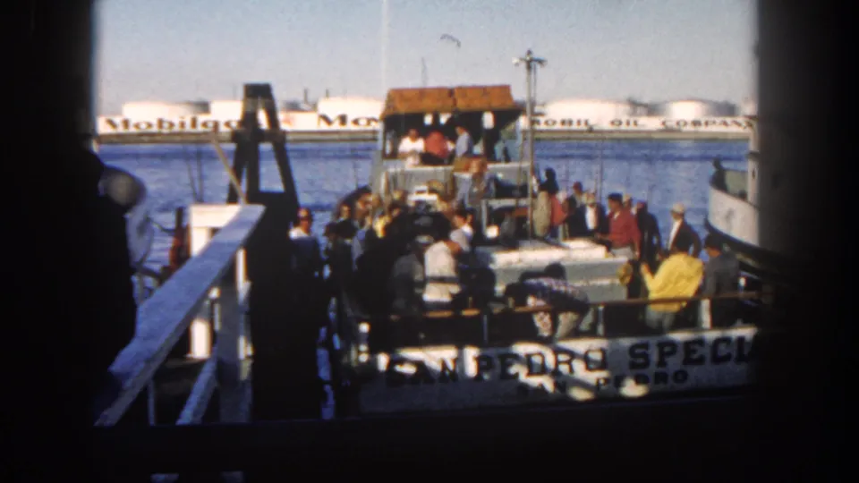 Final frame of the 1962 San Diego marina scene, showing the San Pedro Special, fishermen on the dock and boat, and Mobil Oil tanks beyond the water.