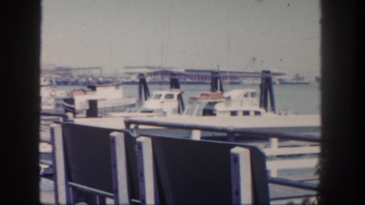 White boats docked beside a pier with benches and railings in the foreground.