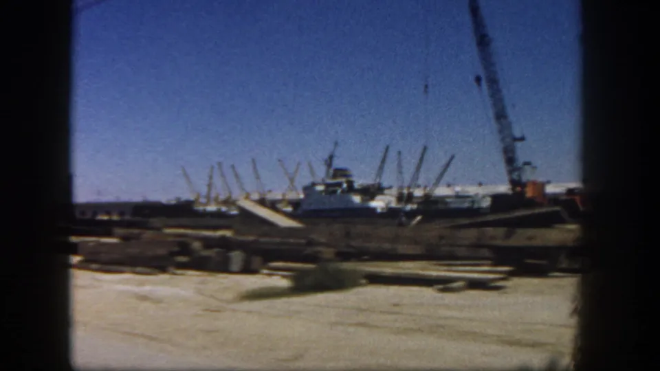 1962 San Diego frame with crane equipment, low industrial structures, and materials spread across a dirt construction site.