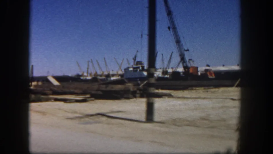 1962 San Diego 8mm frame showing a crane and construction materials partly obscured by a dark vertical foreground edge.