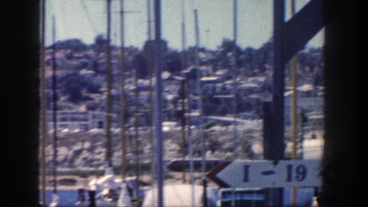 Marina view with sailboat masts, dark posts, hillside buildings, and an I-19 sign.