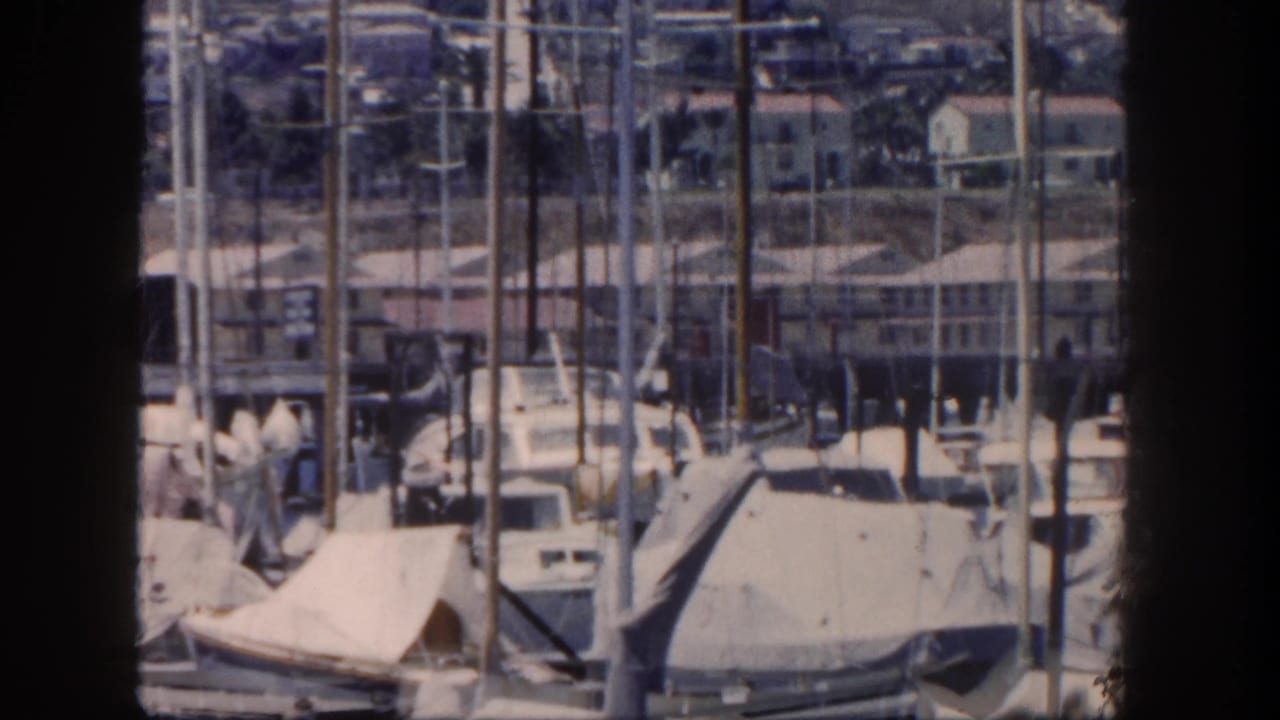 San Diego marina footage from 1962 showing rows of sailboat masts, covered boats, docks, and shoreline buildings.