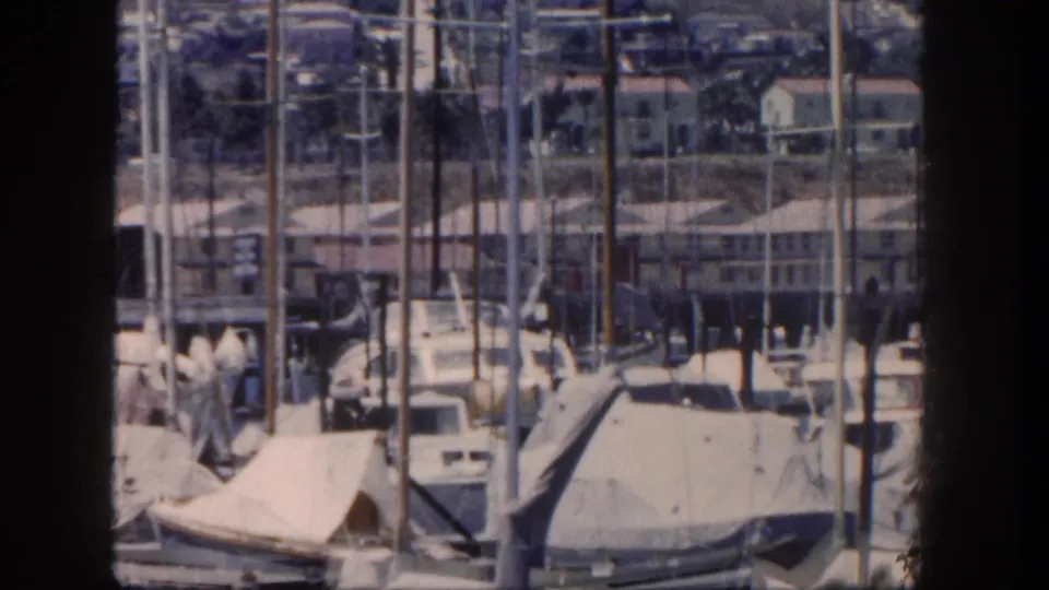 San Diego marina footage from 1962 showing rows of sailboat masts, covered boats, docks, and shoreline buildings.