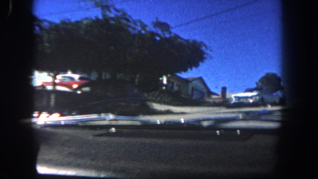 Street and parked cars seen through dark 8mm frame edges near a coastal overlook.