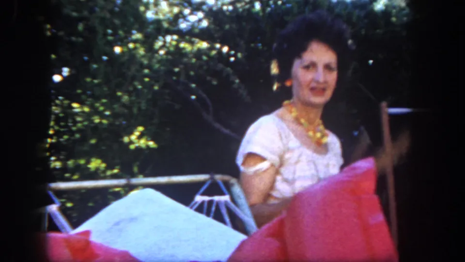 A woman in a white dress appears near bright patio cushions and outdoor furniture in the San Diego backyard scene.