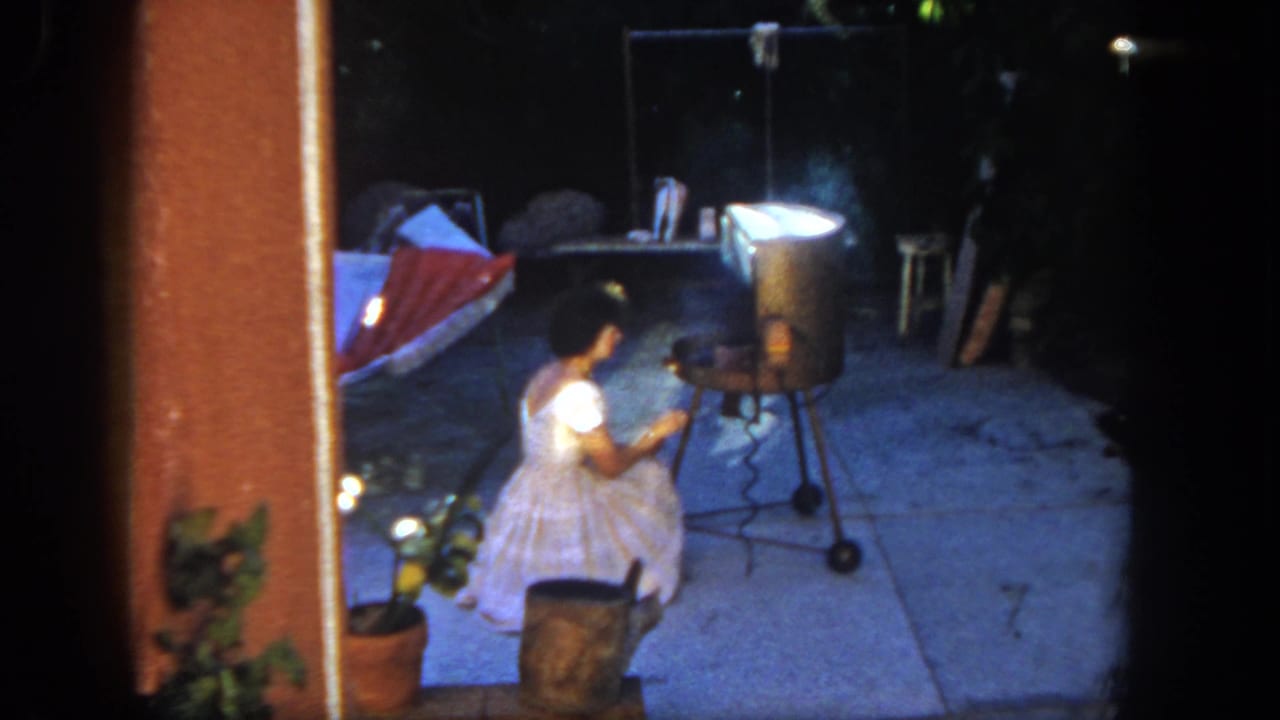 A young girl in a white dress sits at a backyard grill in San Diego, 1962, with smoke rising and a red-and-white hammock in the background.