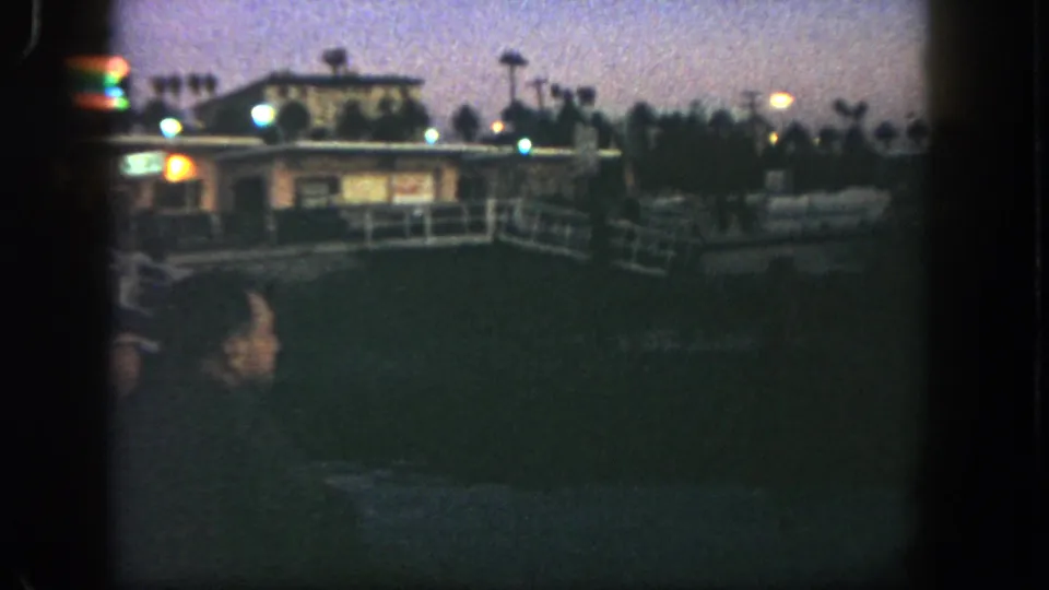 Final 1962 San Diego frame shows a dim commercial exterior with railings, small lights, signs and a dark foreground area.