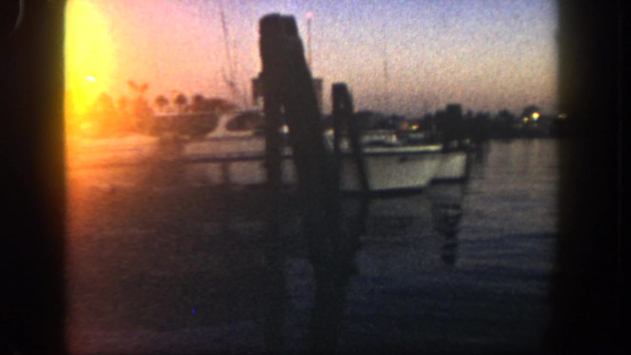 Dusk view across water with dock pilings silhouetted against a bright sunset.