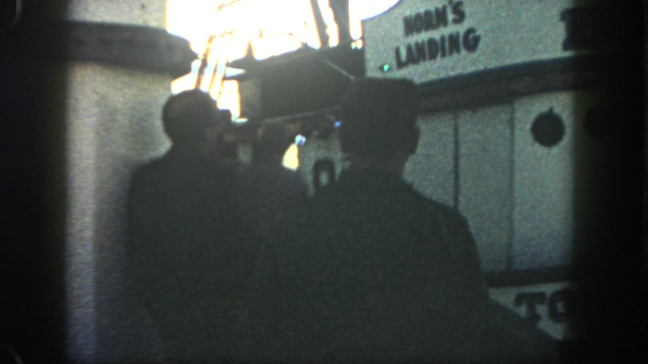 Men in silhouette stand on a San Diego dock near a boat cabin marked Horn's Landing in the 1962 footage.