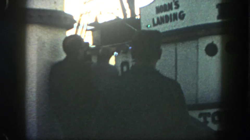 Men in silhouette stand on a San Diego dock near a boat cabin marked Horn's Landing in the 1962 footage.
