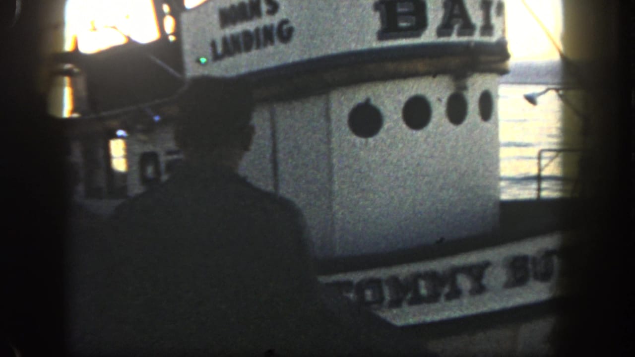 Silhouetted person near a white bait boat with HORN'S LANDING signage and water behind it.