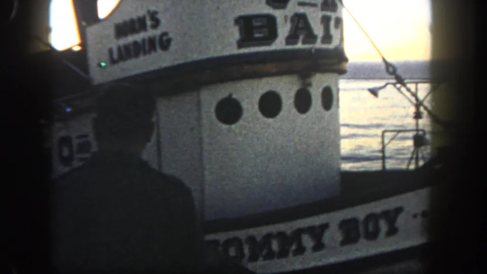 Close 1962 San Diego dock view of a bait boat cabin with O AND K BAIT lettering, round portholes, rigging, and backlit water.