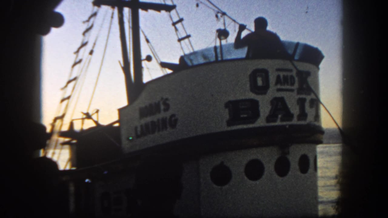Close view of the boat cabin, rigging, portholes, and dark figure on deck.