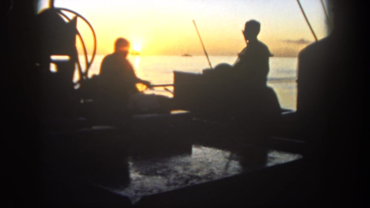 1962 San Diego 8mm footage shows silhouetted men aboard a small boat with fishing gear as the sun sets over the water.
