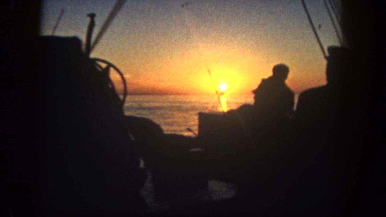 Backlit 8mm view of a person on a boat near rigging and deck gear at sunrise in San Diego, 1962.