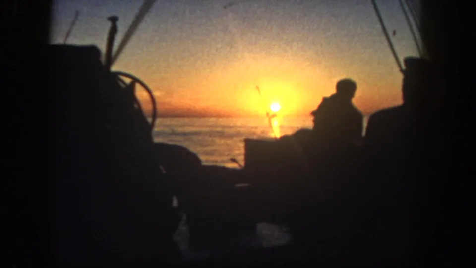 Backlit 8mm view of a person on a boat near rigging and deck gear at sunrise in San Diego, 1962.