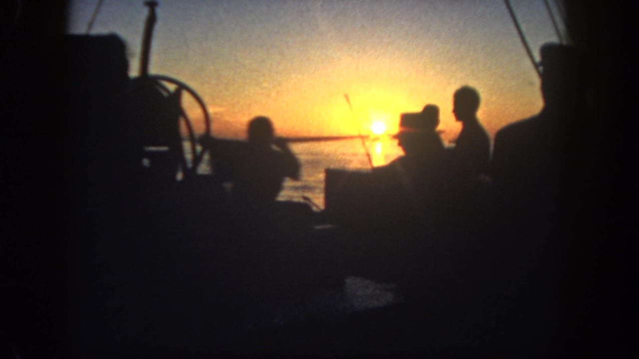 Silhouetted people aboard a small boat at sunset over the water.