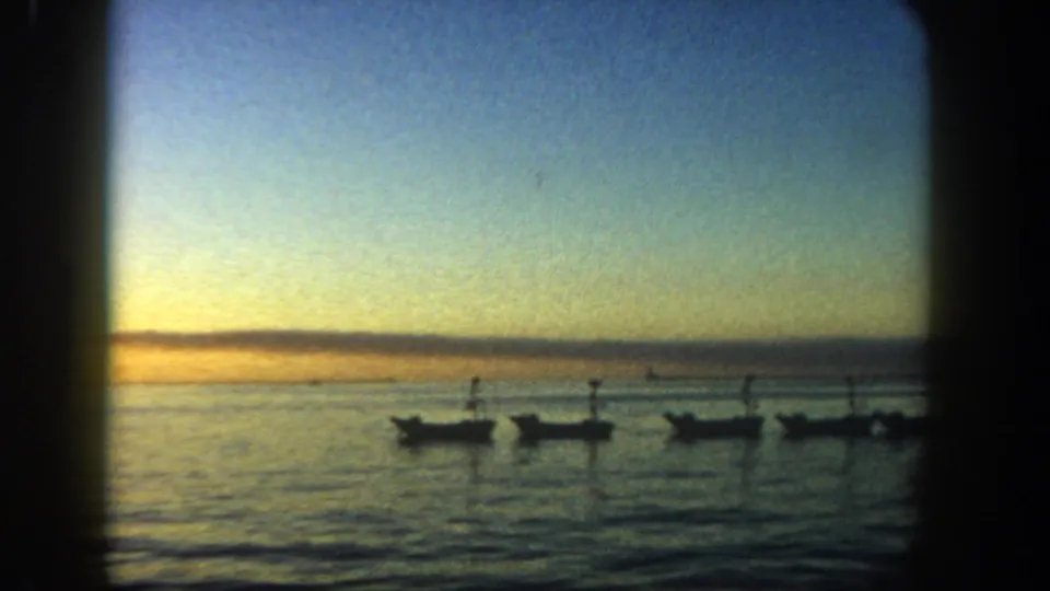 1962 San Diego coastal sunset with calm water, low horizon, and several small silhouetted boats.
