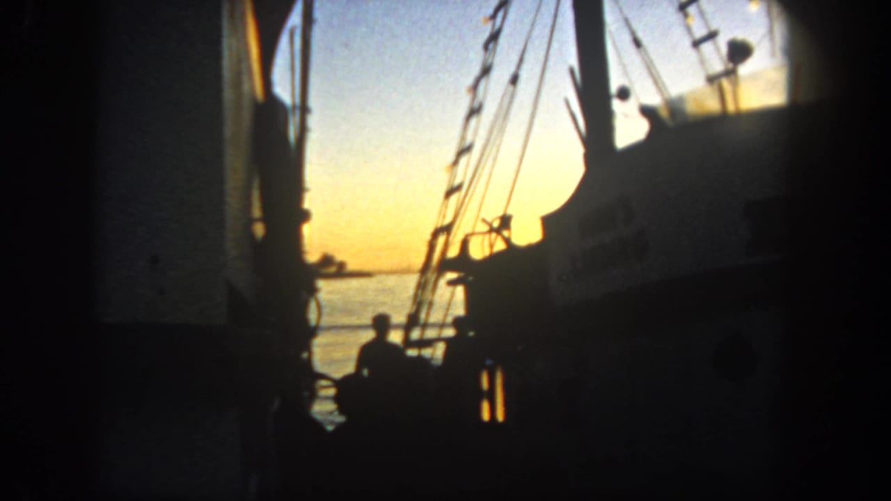 A San Diego harbor boat cabin and mast lines appear in silhouette against a warm 1962 sunset over calm water.
