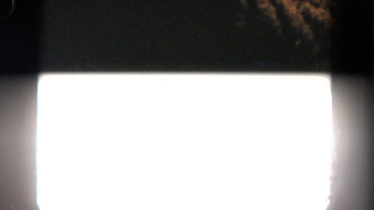 Overexposed 8mm frame from the 1962 San Diego clip, with dark surrounding film area and a bright rectangular flare.