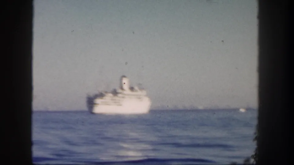 1962 San Diego home-movie view of a white passenger ship moving along the horizon beyond calm blue water.