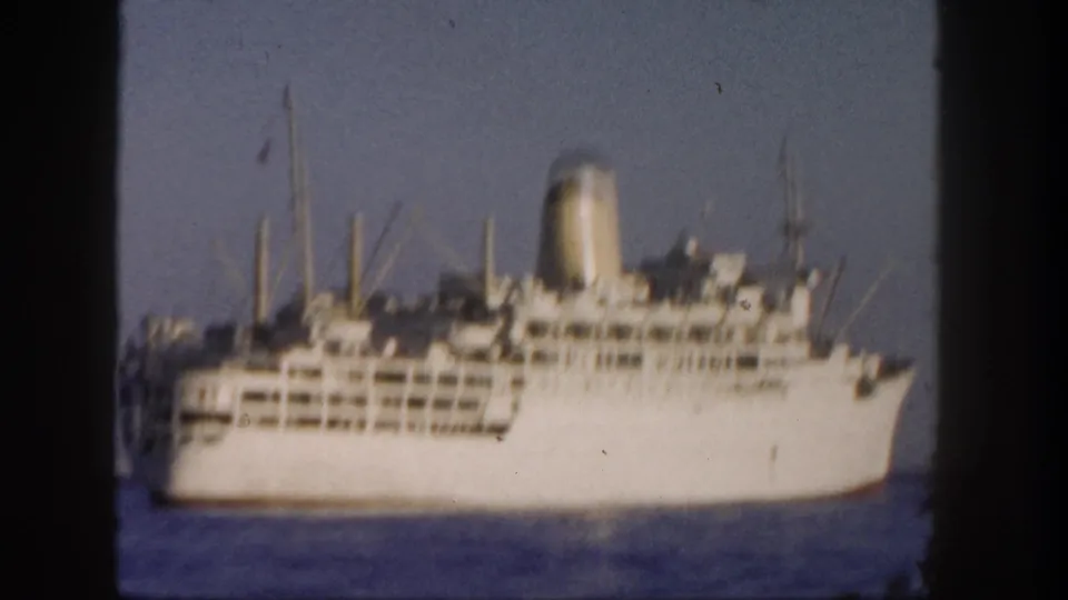 1962 San Diego home-movie frame showing a distant white ocean liner crossing calm Pacific water under a clear sky.